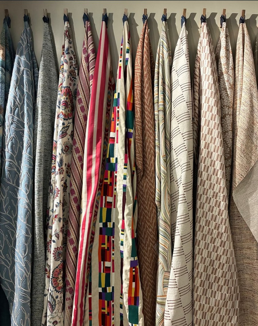 Fabric swatches hanging in the workshop, from patterned to plain weaves